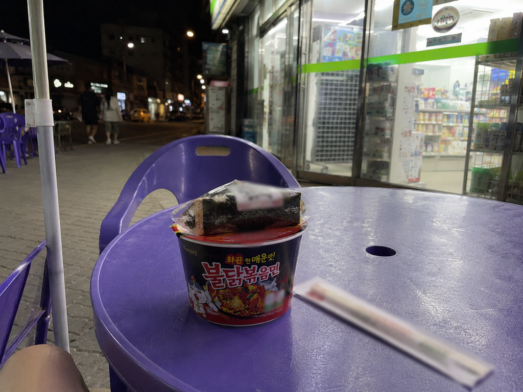 Outdoor tables in front of a Korean convenience store at night