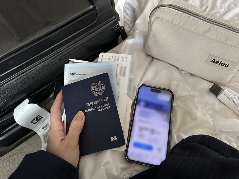 Traveler checking K-ETA requirements with a passport and smartphone before a trip to Korea